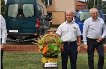 Dwoch mezczyzn, jeden trzyma kosz z symbolicznymi plonami, delegacja Solectwa Rachowa