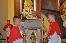 Dwaj ministranci stoja bokiem do obiektywu, miedzy nimi mowinca przy ktorej przemawia ksiadz MArcin Zaworski