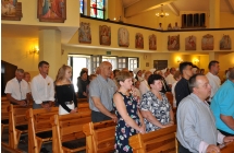 Lawki w ktoych stoja  wierni w trakcie mszy dozynkowej