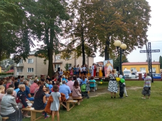 Widzowie siedza przed scena na ktorej stoi grupka dzieci