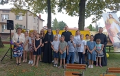 Dzieci po przedstawieniu pozuja z kobieta oraz dwoma ksiezmi