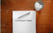 biala kartka z napisem curriculum vitae, z dlugopisem i szklanka wody
