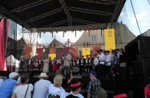 Zespół folklorystyczny na scenie. Pod sceną licznie zebrana publiczność 