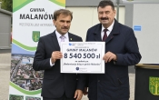 dwóch mężczyzn w garniturach trzyma kartkę 