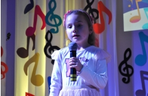 Radosna dziewczynka na scenie ozdobionej w kolorowe nutki 