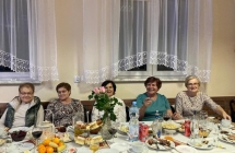 Pięć kobiet siedzących przy zastawionym stole 
