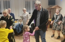 Mężczyzna tańczący z dziewczynką na parkiecie. Dookoła nich wielu zaproszonych gości 