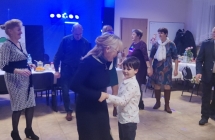 Kobieta tańcząca z chłopcem, dookoła bawiący się ludzie 