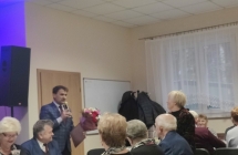 Mężczyzna mówiący do mikrofonu. Przed nim zaproszeni goście 
