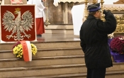 salutujący strażak w tle polskie godło