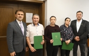 grupa osob, trzy osoby trzymaja w dloniach zielone teczki