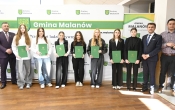 Grupa osób trzyma zielone teczki