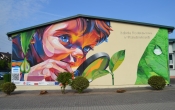 „Kolorowy mural przedstawiajacy dziecko z lupa przygladajace sie przyrodzie – symbol ciekawosci i troski o srodowisko.