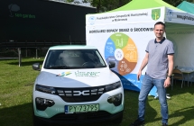 Uśmiechnięty mężczyzna przy samochodzie promującym auta elektryczne oraz ekologię 