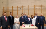 grupa stojacych osob. Przed osobami tort