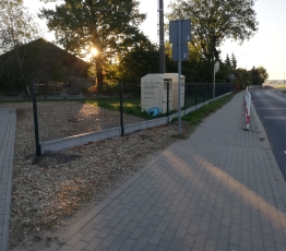 widok na ogrodzenie z siatki obok chodnik i droga