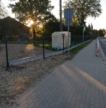 widok na ogrodzenie z siatki obok chodnik i droga