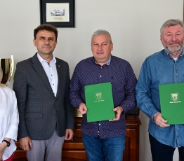 grupa osob, 1 kobieta i 3 mezczyzn, 2 trzyma zielone teczki