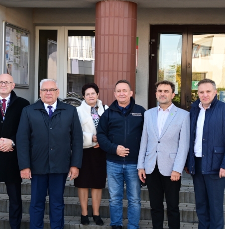 grupa osob stojaca przed budynkiem urzedu gminy